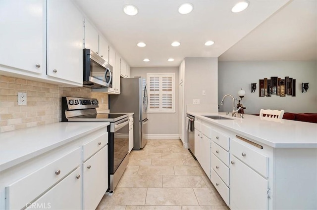 kitchen with recessed lighting, a sink, stainless steel appliances, tasteful backsplash, and a peninsula
