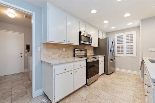 kitchen with stainless steel appliances, light countertops, white cabinetry, backsplash, and baseboards