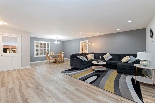 living room featuring recessed lighting, a notable chandelier, and light wood-style floors