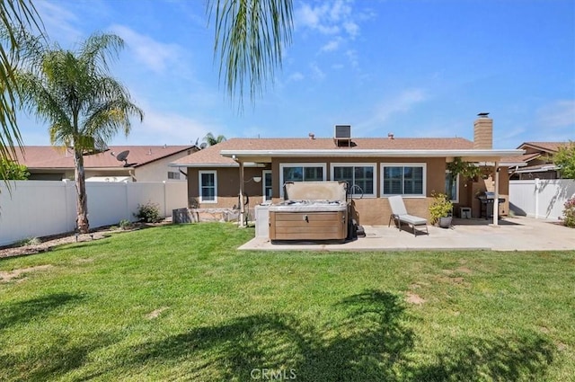 rear view of property with a patio, a chimney, a hot tub, a lawn, and a fenced backyard