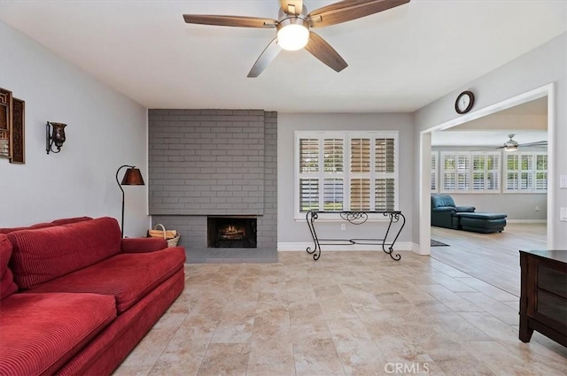 living area with baseboards, ceiling fan, and a fireplace