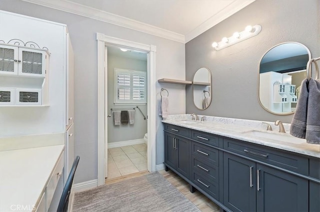 bathroom featuring ornamental molding, toilet, double vanity, and a sink