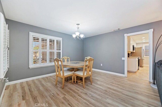 dining area featuring light wood finished floors, visible vents, a chandelier, and baseboards
