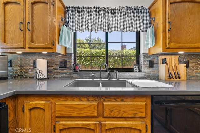 kitchen with brown cabinetry, backsplash, dishwasher, and a sink