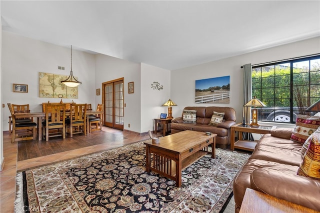 living area featuring baseboards, visible vents, tile patterned flooring, and lofted ceiling
