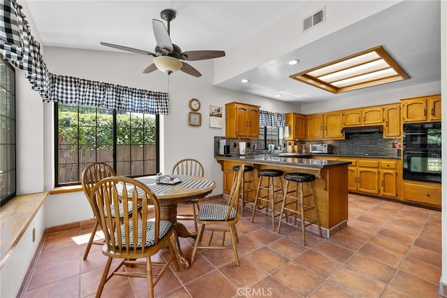 kitchen featuring black appliances, visible vents, a healthy amount of sunlight, and under cabinet range hood