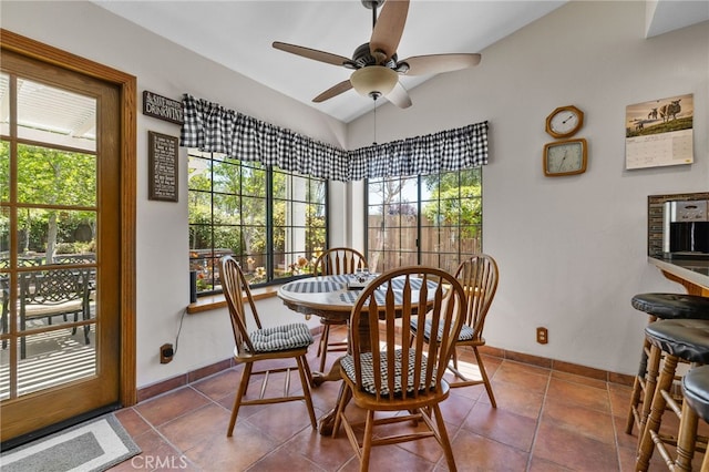 tiled dining room with lofted ceiling, ceiling fan, and baseboards
