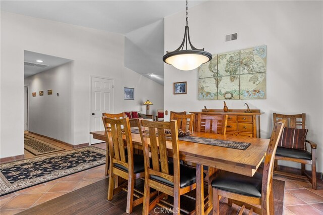 dining area with baseboards, visible vents, and lofted ceiling