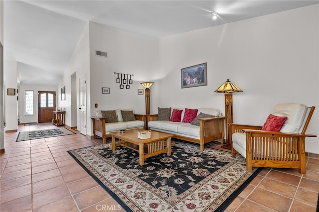 tiled living room featuring baseboards, visible vents, rail lighting, and high vaulted ceiling