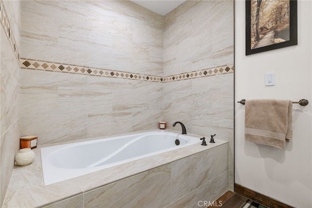 full bathroom featuring tiled bath and baseboards