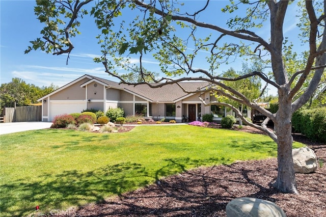 view of front of property featuring driveway, fence, a front yard, and a garage