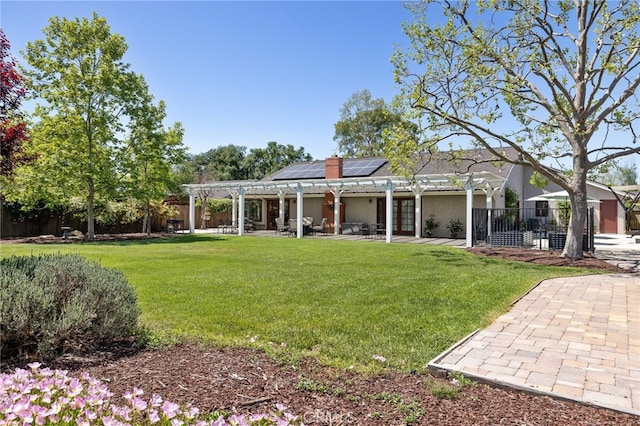 back of house with a pergola, a patio, a fenced backyard, a lawn, and solar panels