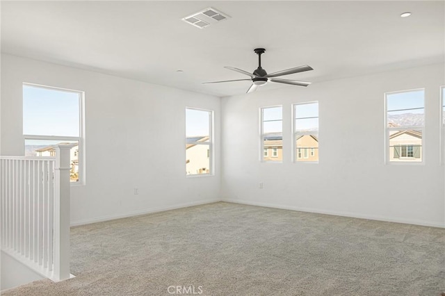 carpeted spare room with visible vents, ceiling fan, and baseboards