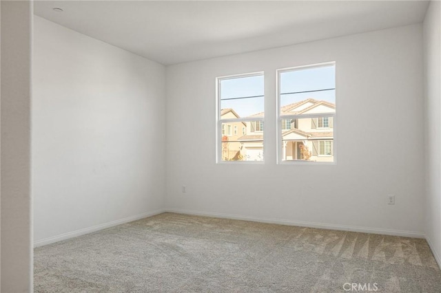 spare room with light colored carpet and baseboards