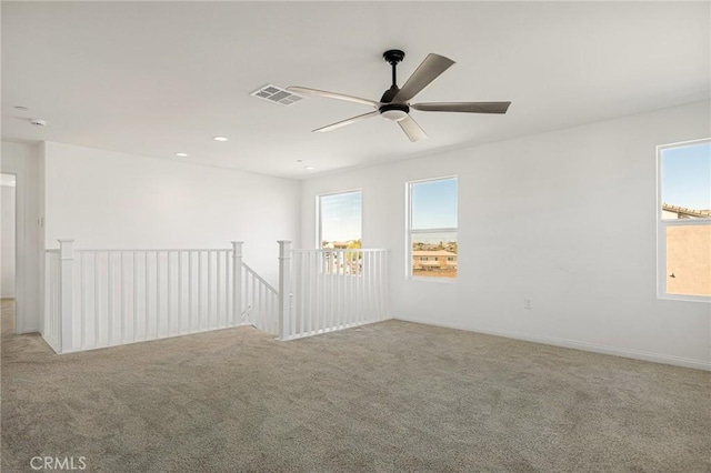empty room with visible vents, a ceiling fan, and carpet floors