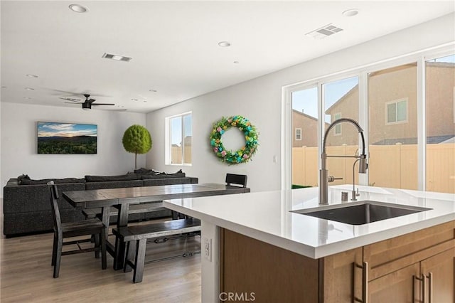 kitchen featuring visible vents, light wood finished floors, light countertops, and a sink
