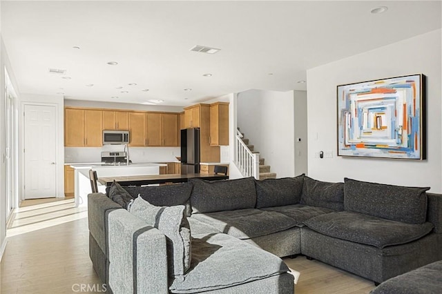 living area featuring visible vents, light wood-type flooring, stairs, and recessed lighting