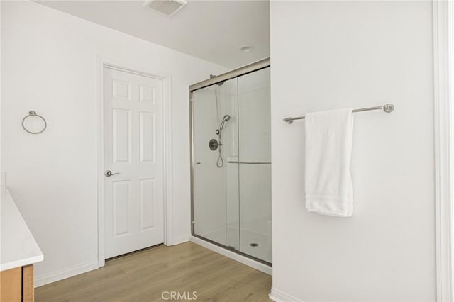 bathroom featuring a shower stall, visible vents, baseboards, wood finished floors, and vanity