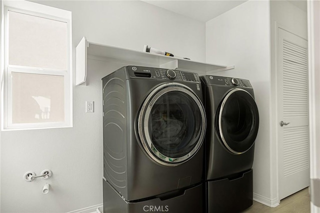 clothes washing area with washer and dryer, laundry area, and baseboards