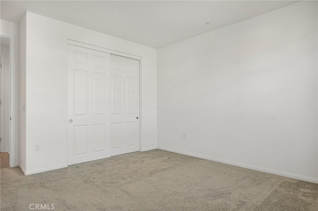 unfurnished bedroom with carpet, a closet, and baseboards