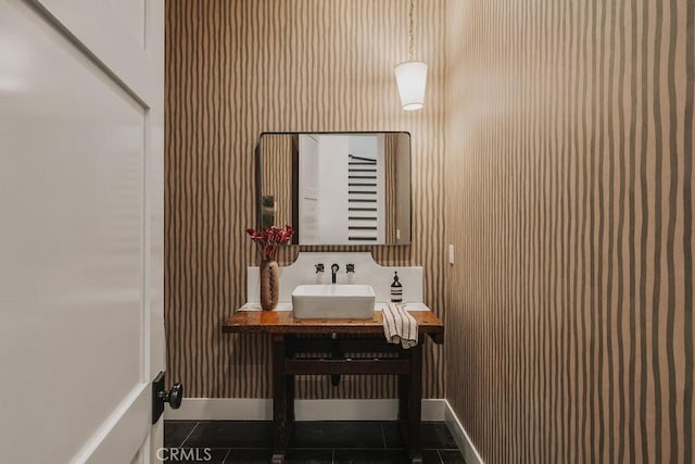 bathroom featuring baseboards, a sink, and tile patterned floors