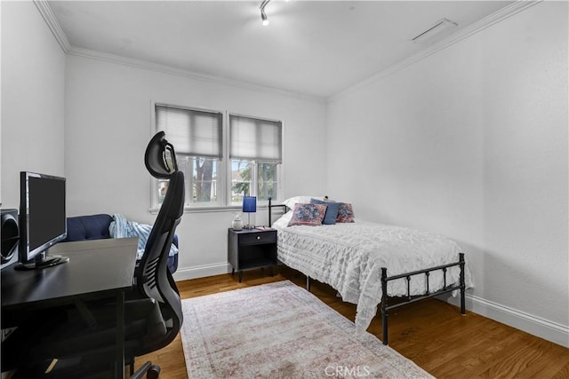 bedroom featuring baseboards, crown molding, and wood finished floors