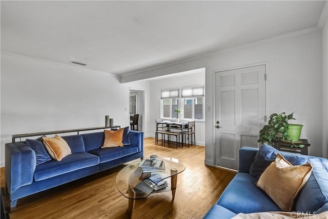 living area with visible vents, ornamental molding, baseboards, and wood finished floors