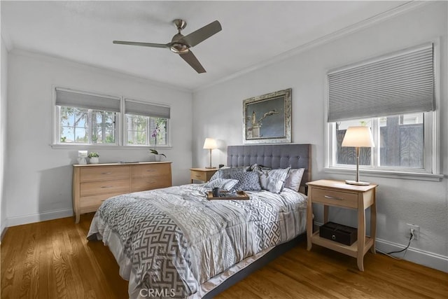 bedroom featuring baseboards, crown molding, wood finished floors, and ceiling fan