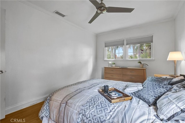 bedroom featuring crown molding, baseboards, wood finished floors, and visible vents