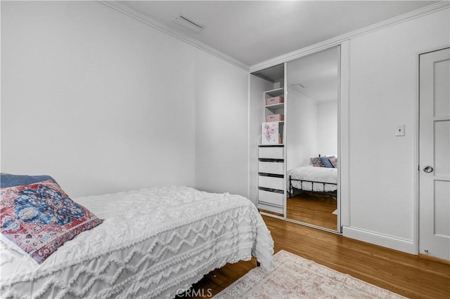 bedroom featuring crown molding, baseboards, a closet, and wood finished floors
