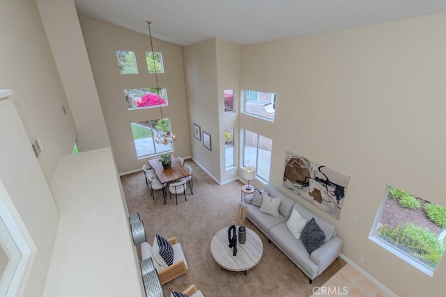 living room with high vaulted ceiling, baseboards, and carpet