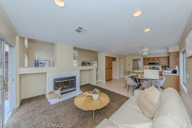 living room with a ceiling fan, visible vents, a fireplace with flush hearth, baseboards, and recessed lighting