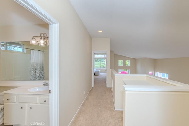 hall with light carpet, a sink, recessed lighting, baseboards, and an upstairs landing