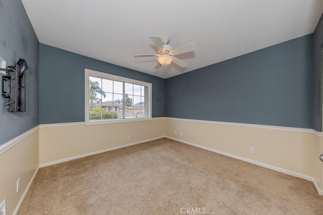 carpeted empty room with a ceiling fan and baseboards