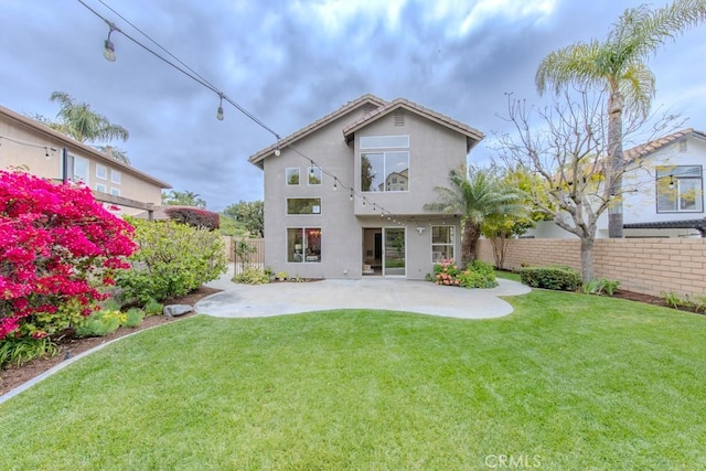 back of property with a fenced backyard, a patio, stucco siding, and a yard