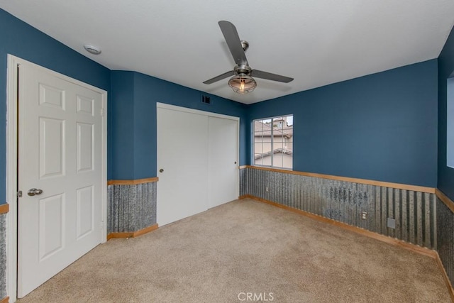 unfurnished bedroom with ceiling fan, visible vents, carpet, and a closet