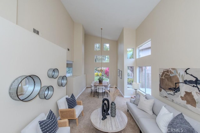 living room featuring an inviting chandelier, high vaulted ceiling, baseboards, and carpet flooring