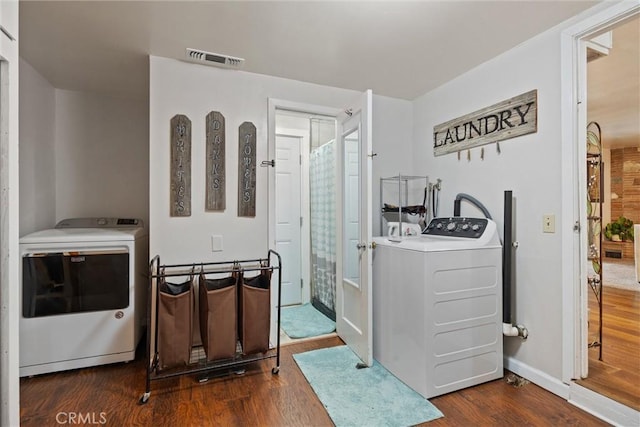 interior space featuring separate washer and dryer, laundry area, visible vents, baseboards, and wood finished floors