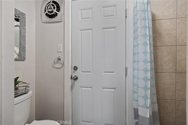 full bath featuring toilet and a shower with shower curtain