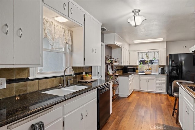 kitchen with black appliances, visible vents, white cabinetry, and a sink