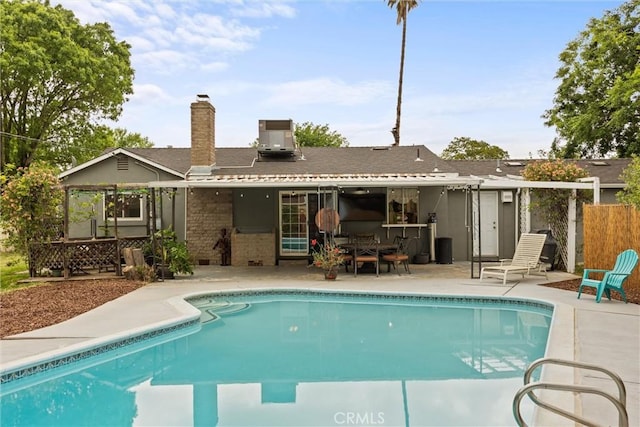 rear view of property featuring a patio, a fenced in pool, a chimney, fence, and brick siding