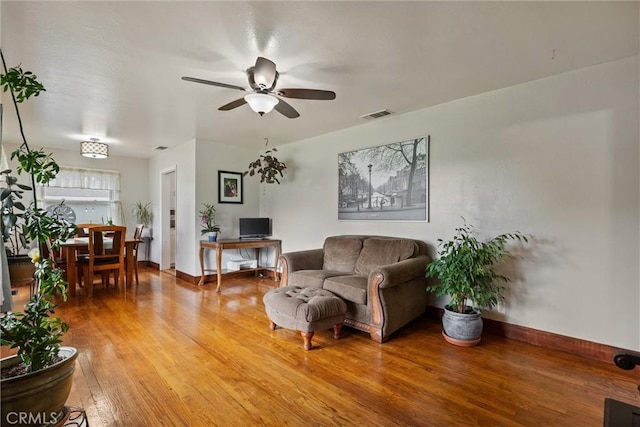 living room with visible vents, a ceiling fan, baseboards, and light wood-style floors