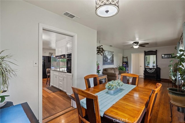 dining space with a ceiling fan, visible vents, and wood finished floors
