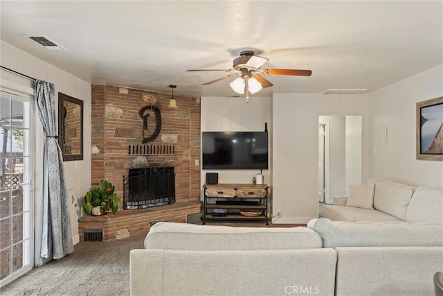 carpeted living room with a ceiling fan, visible vents, and a fireplace