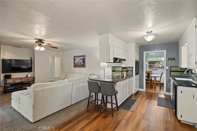 kitchen featuring a sink, black appliances, white cabinetry, dark countertops, and open floor plan