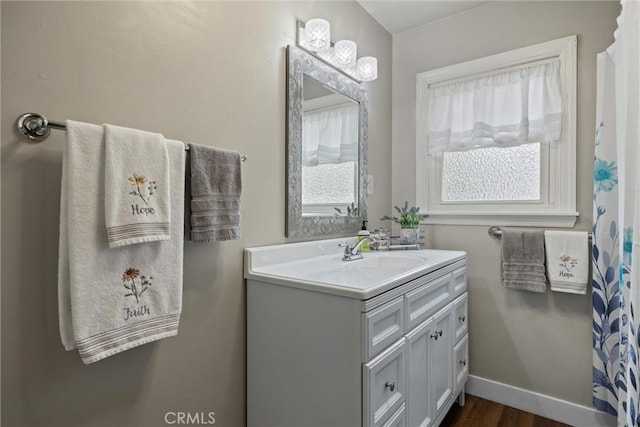 full bath with wood finished floors, vanity, and baseboards