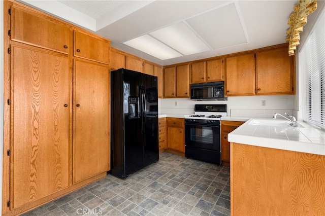 819 Miller Rd, Banning, CA 92220 - kitchen with stone finish floor, a sink, black appliances, tile countertops, and brown cabinetry