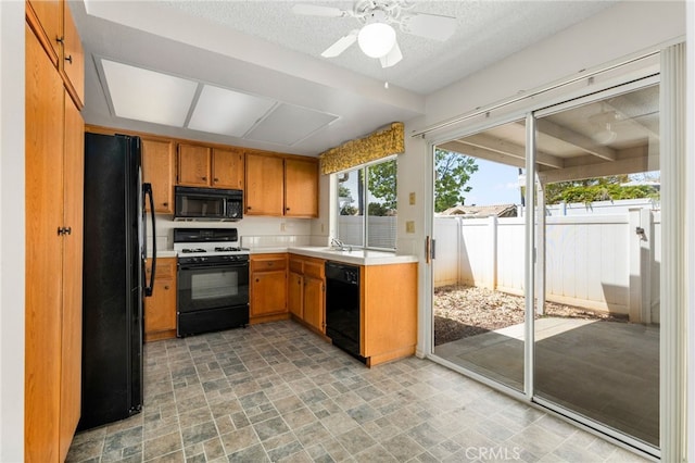 819 Miller Rd, Banning, CA 92220 - kitchen featuring stone finish floor, brown cabinets, light countertops, black appliances, and a ceiling fan