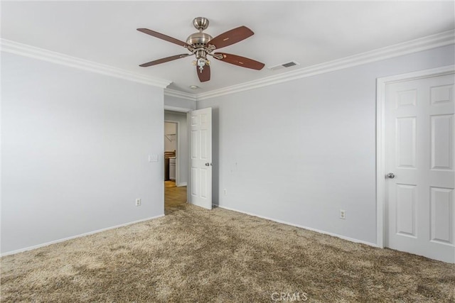 carpeted empty room featuring baseboards, visible vents, a ceiling fan, and crown molding