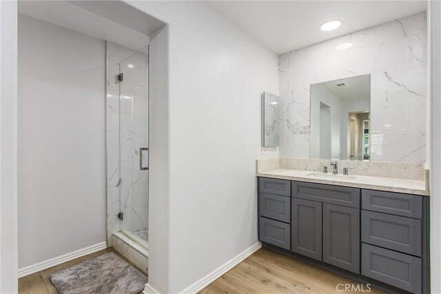bathroom with wood finished floors, vanity, recessed lighting, and a marble finish shower
